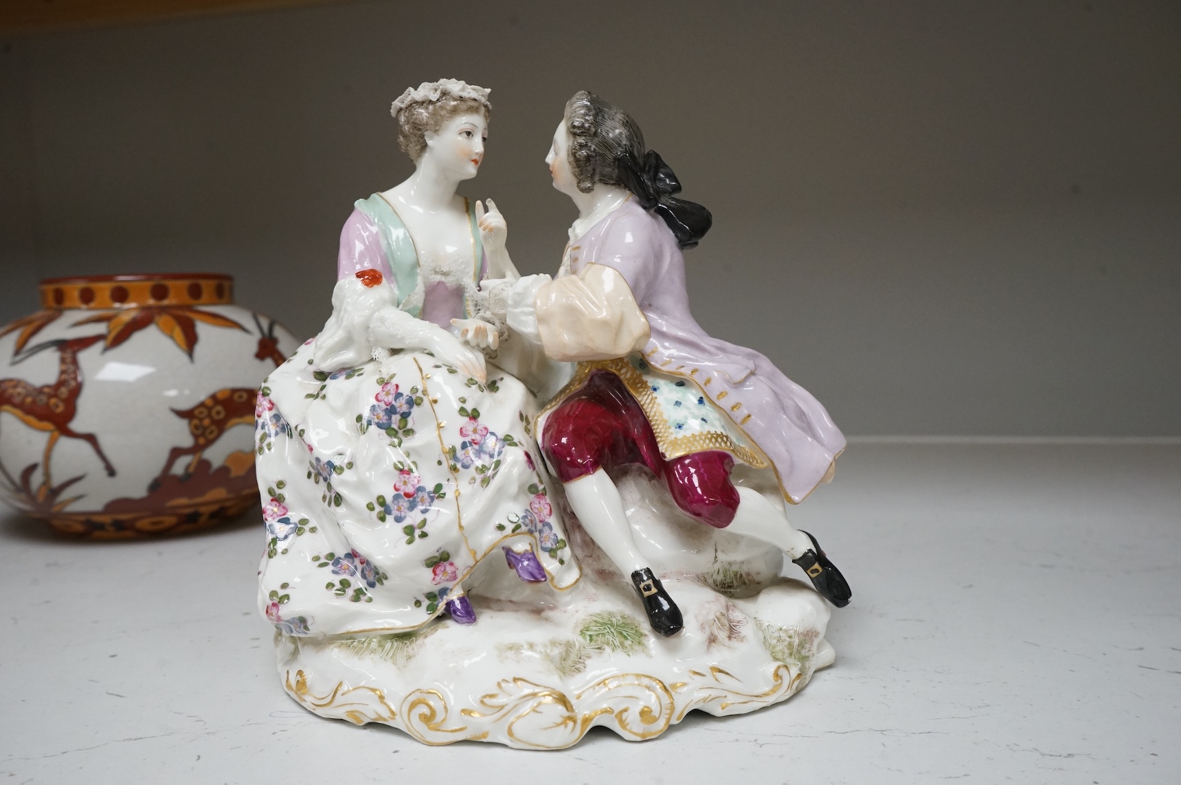 A German porcelain group of a seated courting couple, 16.5cm high